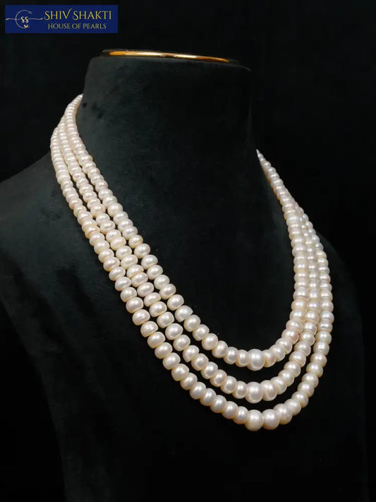 Three-strand pearl necklace on a black mannequin