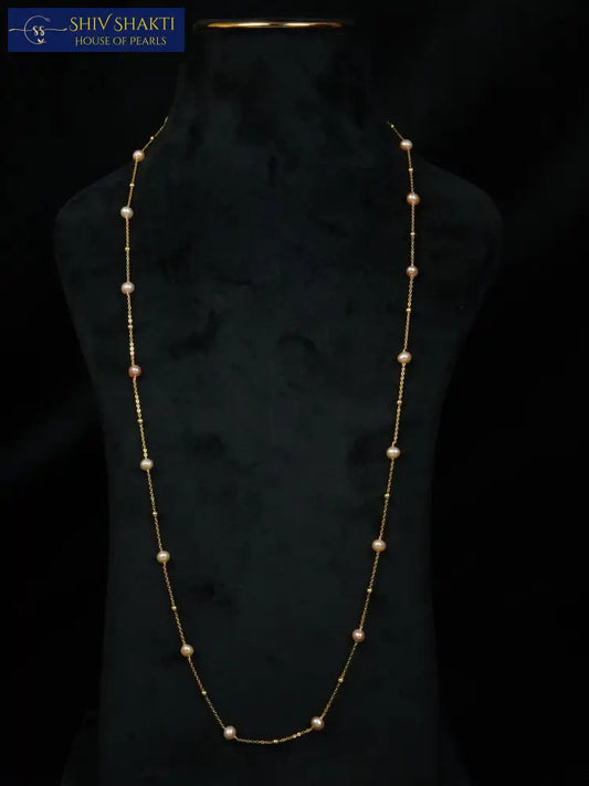Long pearl necklace on a black mannequin against a dark background