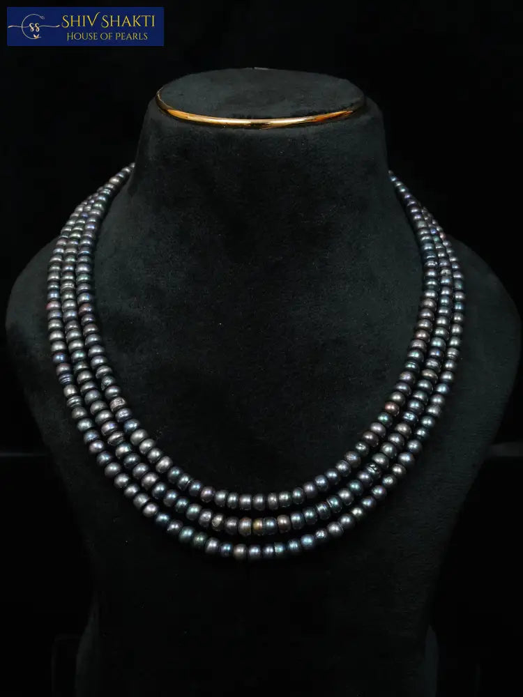 Necklace displayed on a black mannequin bust against a black background