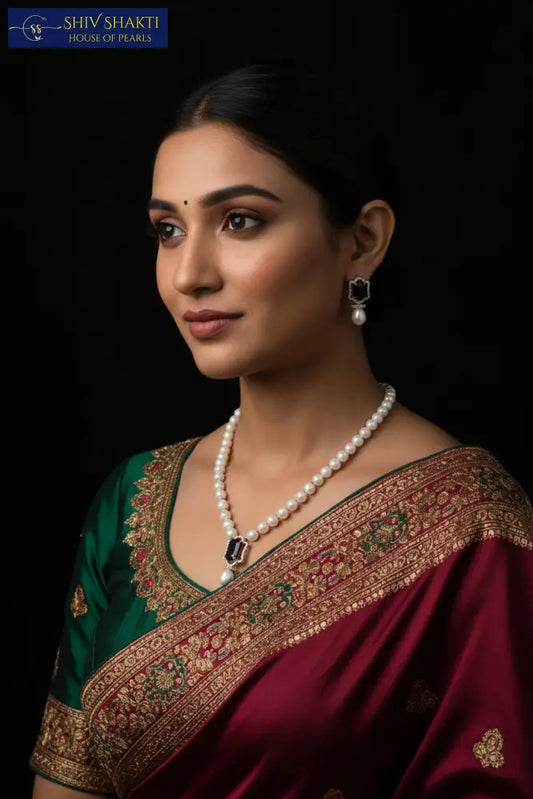Pearl necklace with pendant on a black mannequin and matching earrings on a black background