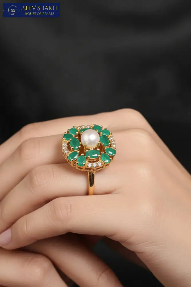 Golden ring with green gemstones on a black velvet stand against a dark background