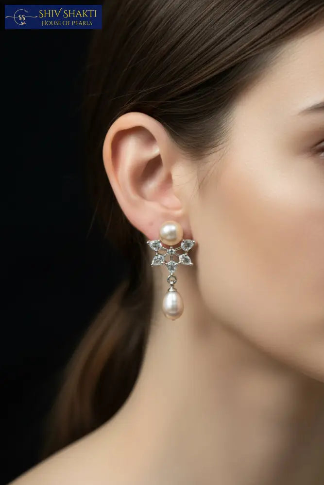 Pair of pearl earrings with diamond-like stones on a black background