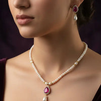 Pearl necklace with red gemstones on a black mannequin against a dark background