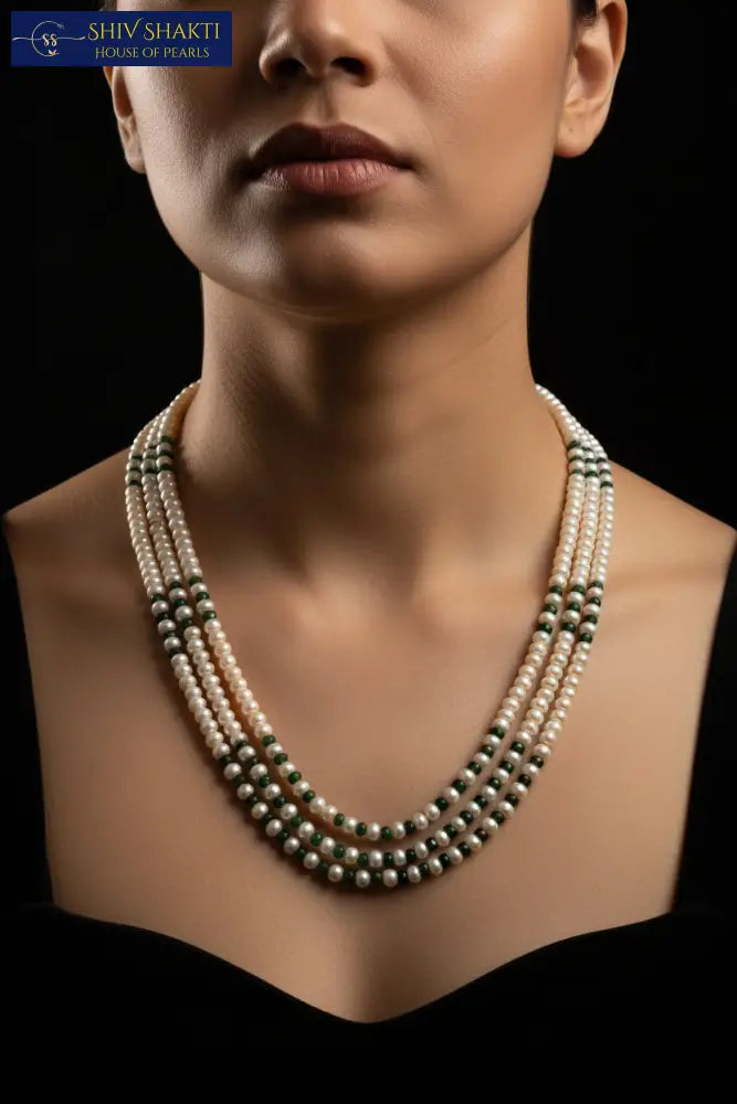 Pearl necklace with green accents on a black mannequin