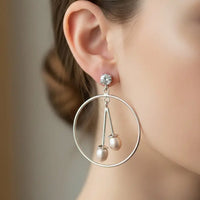 Pair of silver hoop earrings with pearl drops on a black background