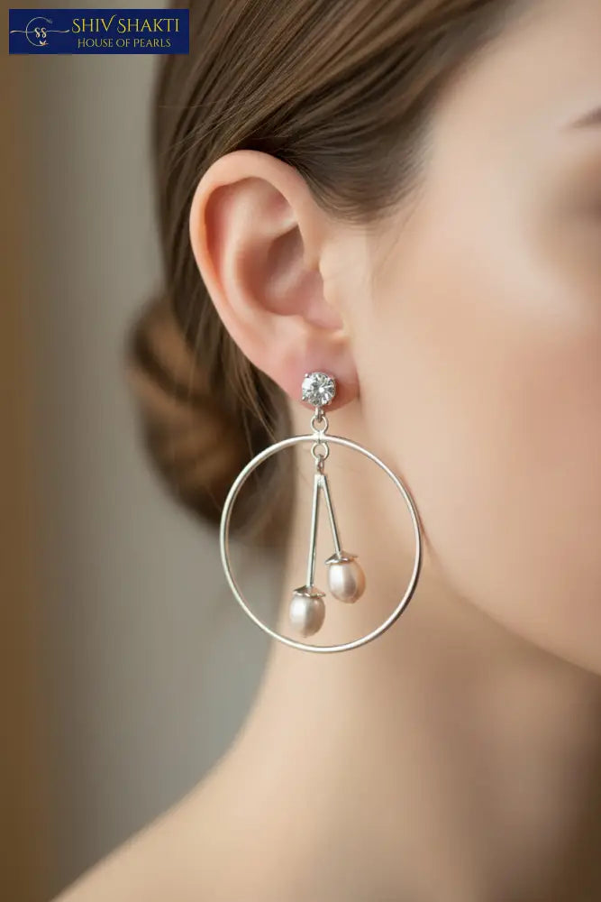 Pair of silver hoop earrings with pearl drops on a black background