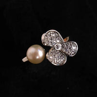 Jewelry with a pearl and diamond-studded flower design on a black background
