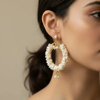 Pair of pearl hoop earrings with gold accents on a black background
