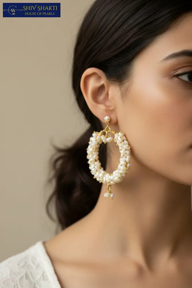 Pair of pearl hoop earrings with gold accents on a black background