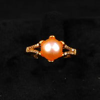 Gold ring with a large orange gemstone on a black background