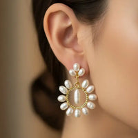 Pair of pearl earrings with gold circular frames on a black background