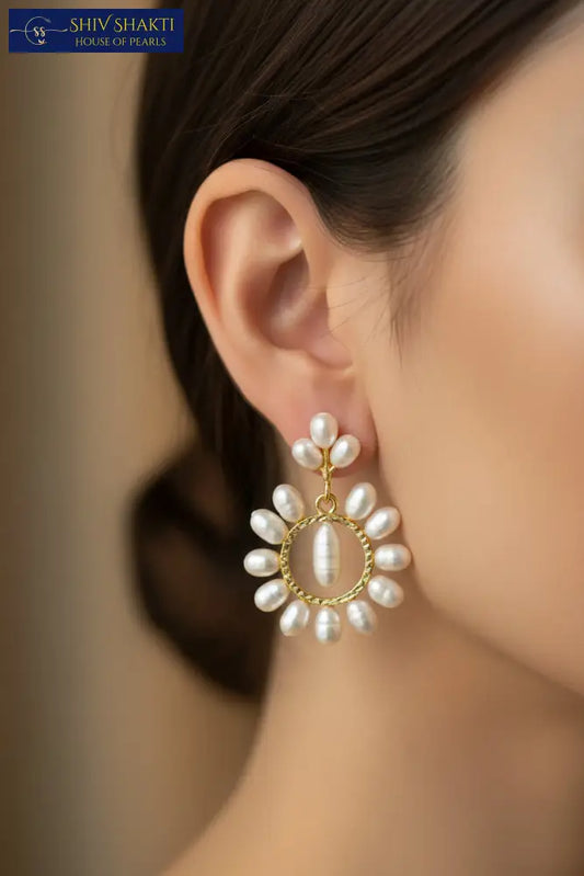 Pair of pearl earrings with gold circular frames on a black background