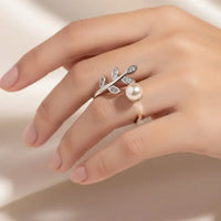 Silver ring with leaf design and pearl on a black background