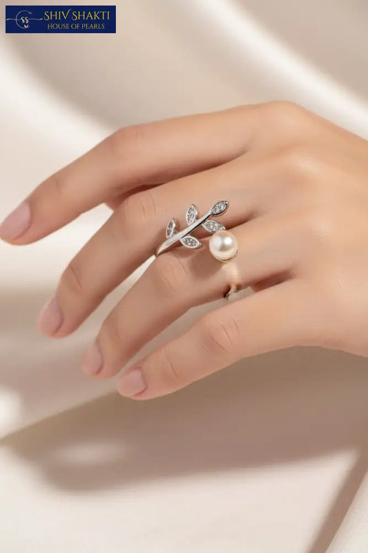 Silver ring with leaf design and pearl on a black background