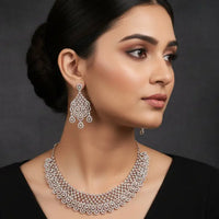 Silver necklace and earrings on a black stand with a black background