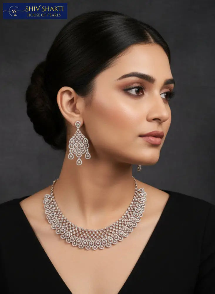 Silver necklace and earrings on a black stand with a black background