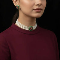 Woman wearing a pearl necklace and earrings with a black saree against a dark background