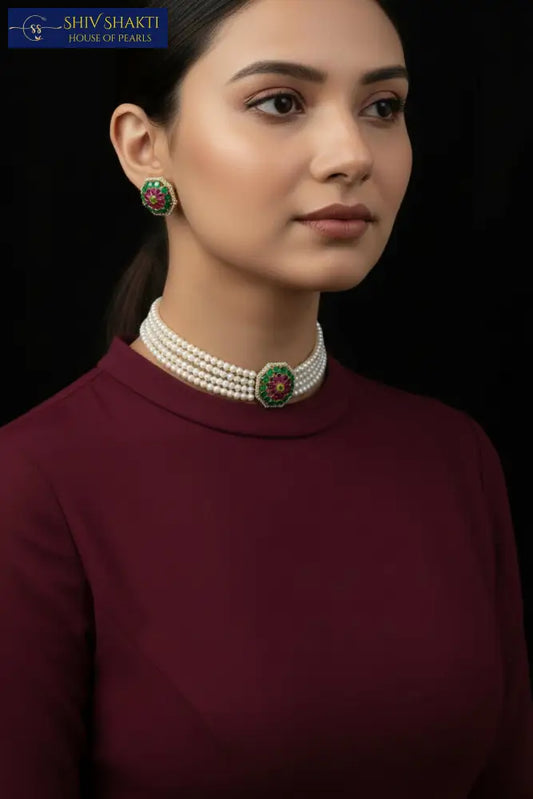 Woman wearing a pearl necklace and earrings with a black saree against a dark background